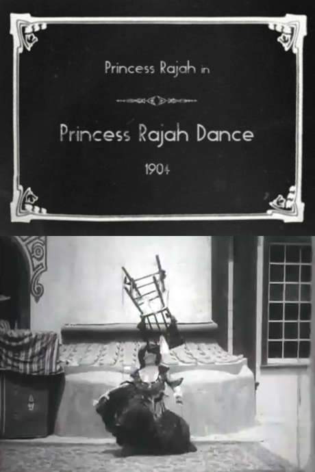 A woman stands before a building, a chair placed to her left. She wears a black ensemble with a full skirt, quarter‑length sleeves and a scooped‑neck bodice, her hair piled high atop her head. After a slight bow, she lifts finger cymbals and begins the cooch, moving gracefully in rhythm.